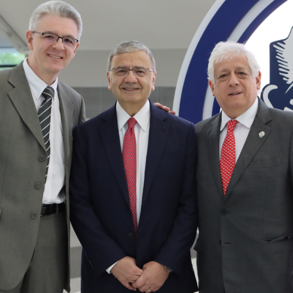 Three men in suits smile at the camera.