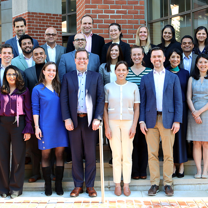 A group of 20 adults stand outside a brick building.
