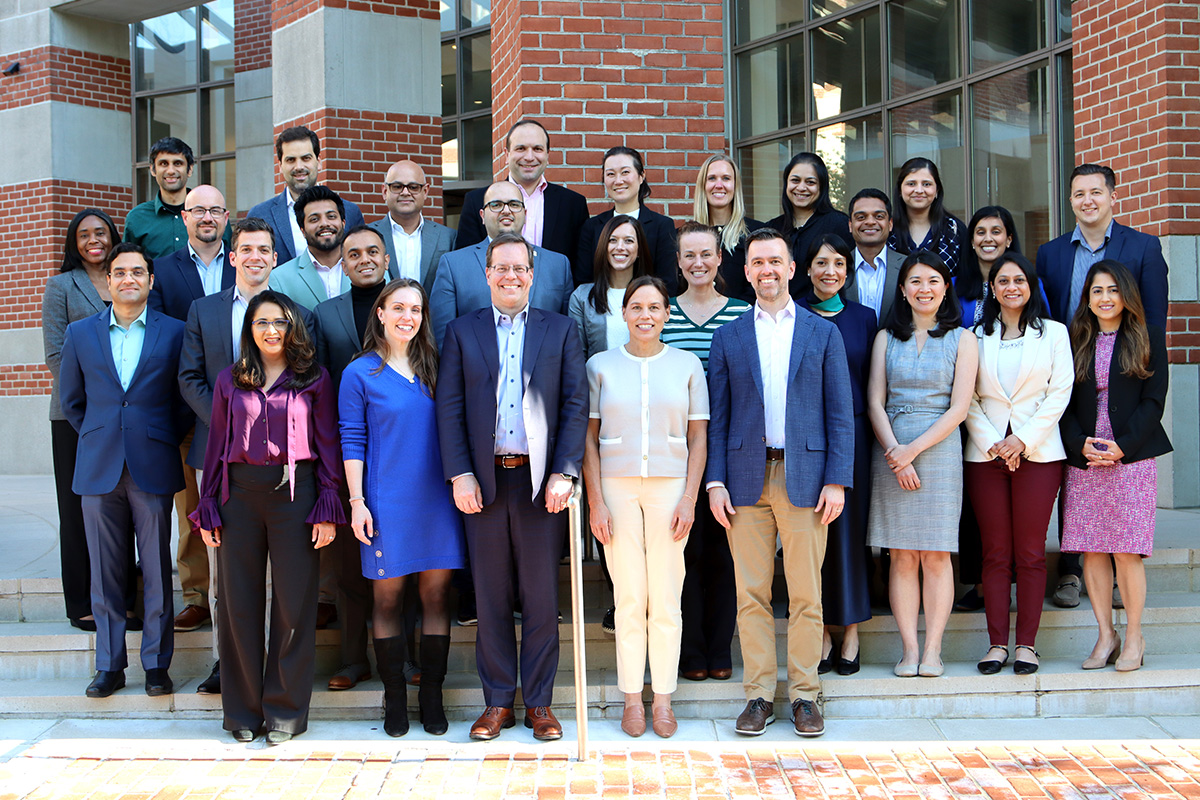 A group of 20 adults stand outside a brick building.